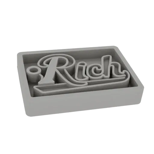 Render 3D di un tagliabiscotti grigio con la parola 'Rich' in un font corsivo stilizzato.