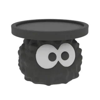 Modello 3D di un Soot Sprite nero e soffice con grandi occhi bianchi, sormontato da una piattaforma circolare scura.