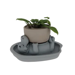 Modelo 3D de un hipopótamo gris tumbado de espaldas, sosteniendo una maceta beige con hojas verdes.