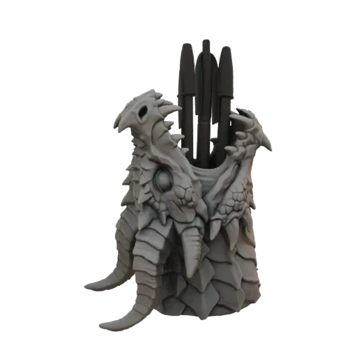 A detailed 3D model of a grey dragon head with sharp teeth, designed as a pen holder, with pens visible inside its mouth.
