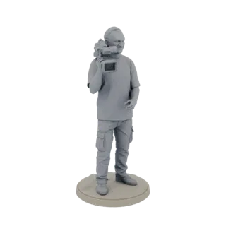3D model of a male videographer standing on a base, holding a camera over his shoulder.