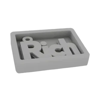 Un rendering 3D di uno stampo in silicone grigio con la scritta 'Rich' in rilievo all'interno, pronto per la colata.