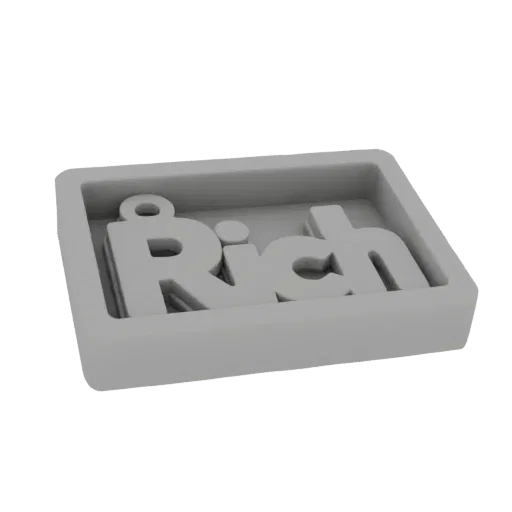 Una renderización 3D de un molde de silicona gris con la palabra 'Rich' en relieve en su interior, listo para fundición.