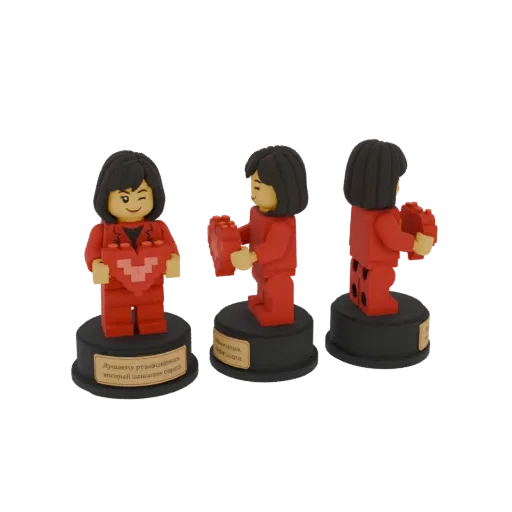 A 3D render of a Lego-style figurine in a red suit, winking and holding a pixelated red heart, displayed on a black base.