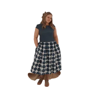 Modello 3D di donna in piedi con mani in tasca, indossa un top blu e una gonna a pois blu navy e bianchi.