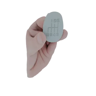 3D model of a light gray, oval-shaped 5-speed manual gear shift knob with the 'H' pattern embossed on its surface, held by a