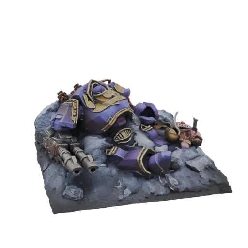 3D model of a fallen purple Space Marine Terminator lying on a rocky terrain base, with a large bolter weapon beside it.