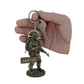 3D-Modell eines russischen Soldaten-Schlüsselanhängers mit AK-47-Gewehr und 'Святой'-Plakette, in der Hand gehalten.